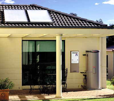 Roof-mounted solar collectors teamed with ground-level tank and gas booster heater.